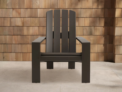 Powder-coated dark bronze Adirondack outdoor aluminum lounge chair, angled against a wooden shingle wall on light pavement.