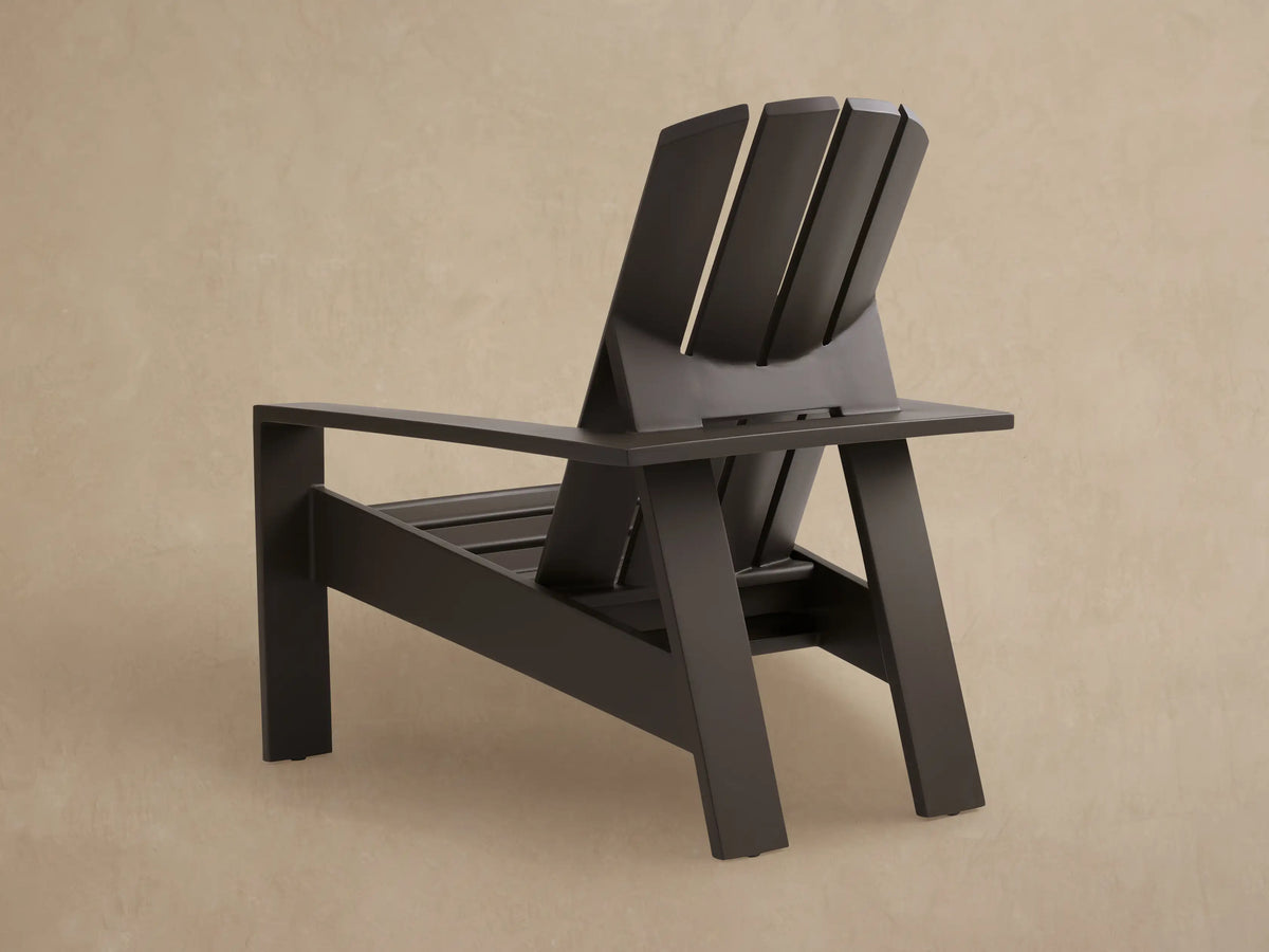 Angled, close-up view of a dark bronze aluminum Adirondack lounge chair, highlighting its slatted backrest and seat.