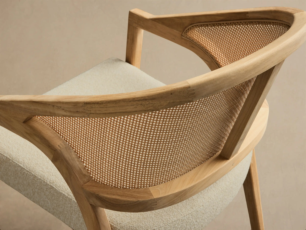 Close-up of the Aimee Outdoor Dining Chair with natural teak wood frame, light beige resin caning backrest, and off-white seat cushion.
