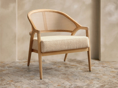 Front view of the Aimee Outdoor Lounge Chair featuring a light teak wood frame, woven resin caning back, and a textured beige cushion.