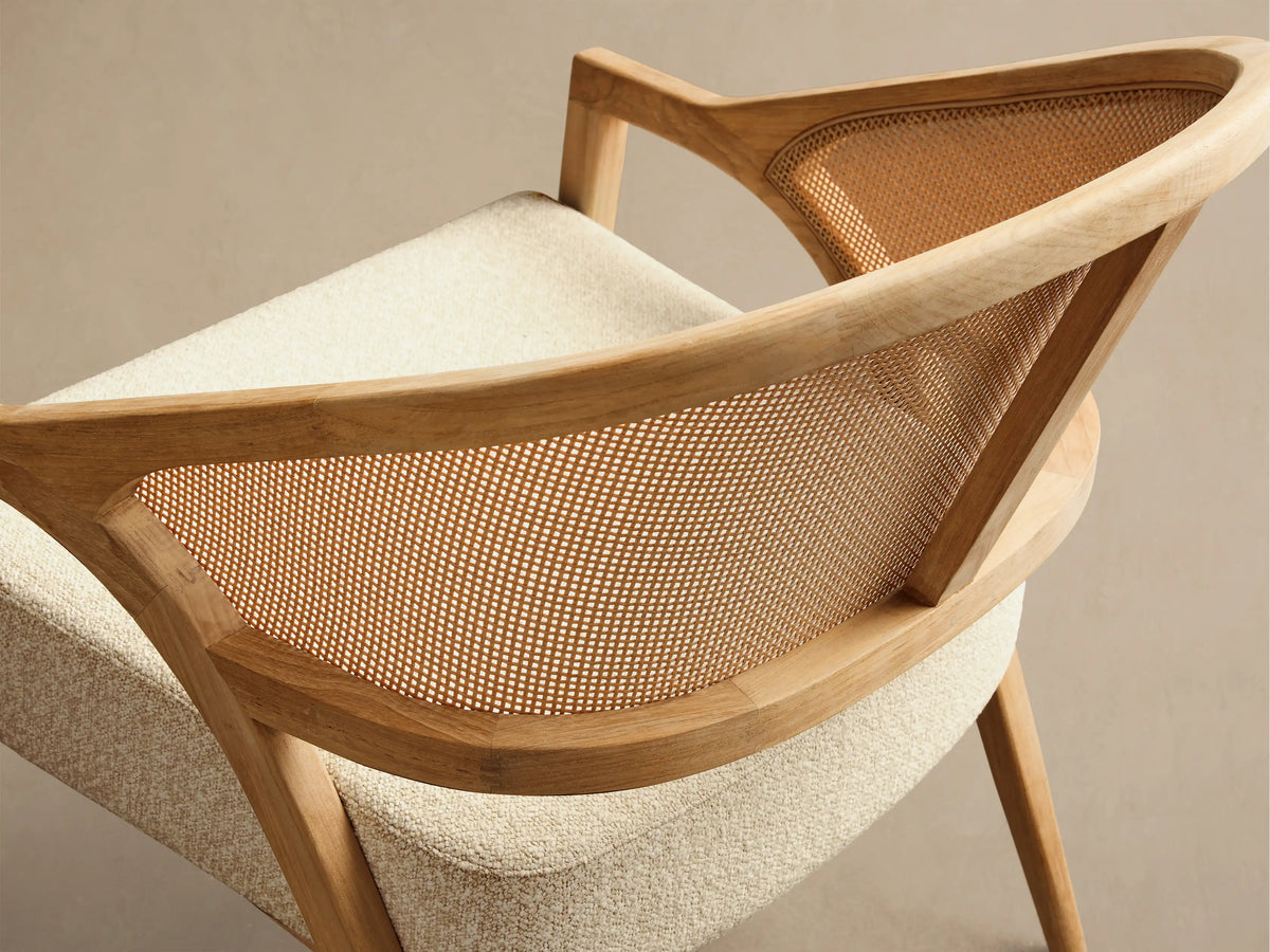 Front view of the Aimee Outdoor Lounge Chair featuring a light teak wood frame, woven resin caning back, and a textured beige cushion.