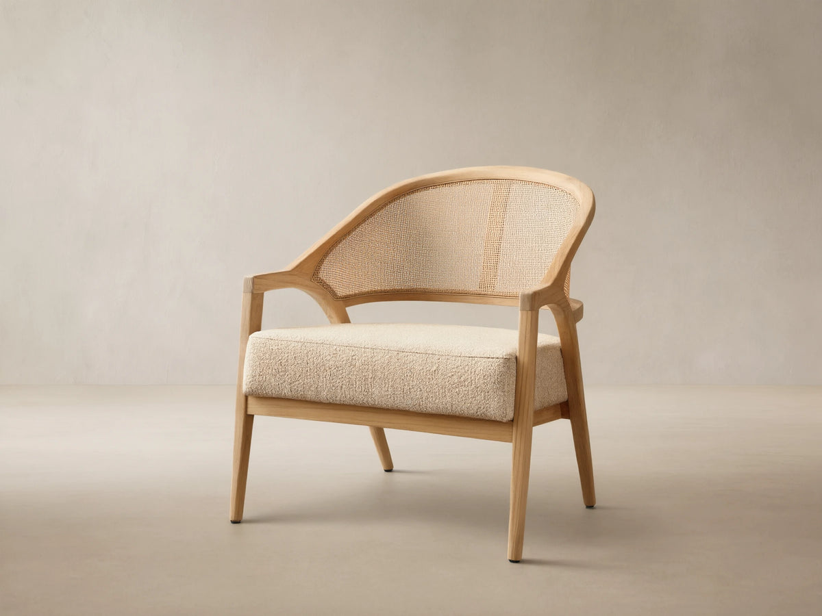 Front view of the Aimee Outdoor Lounge Chair featuring a light teak wood frame, woven resin caning back, and a textured beige cushion.