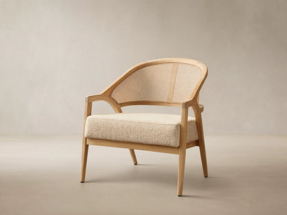 Front view of the Aimee Outdoor Lounge Chair featuring a light teak wood frame, woven resin caning back, and a textured beige cushion.