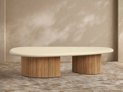 Alesso Outdoor Coffee Table with a light beige oval top and two cylindrical natural wood slatted bases, on a stone patio.
