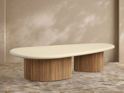 Alesso Outdoor Coffee Table with a light beige oval top and two cylindrical natural wood slatted bases, on a stone patio.