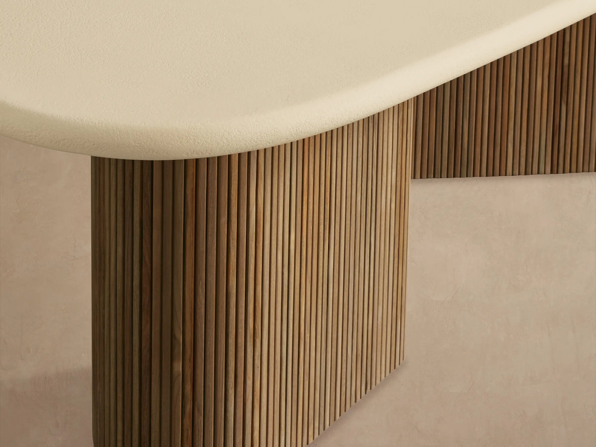 Alesso Outdoor Dining Table with an oval beige top and two ridged, natural teak cylindrical bases on a tiled floor.