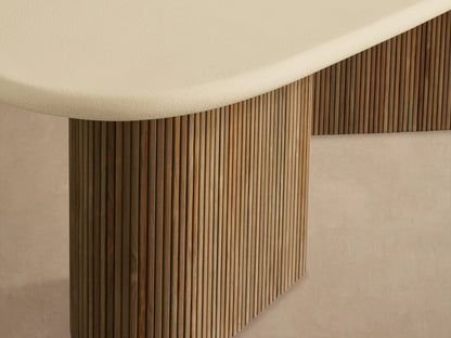 Alesso Outdoor Dining Table with an oval beige top and two ridged, natural teak cylindrical bases on a tiled floor.