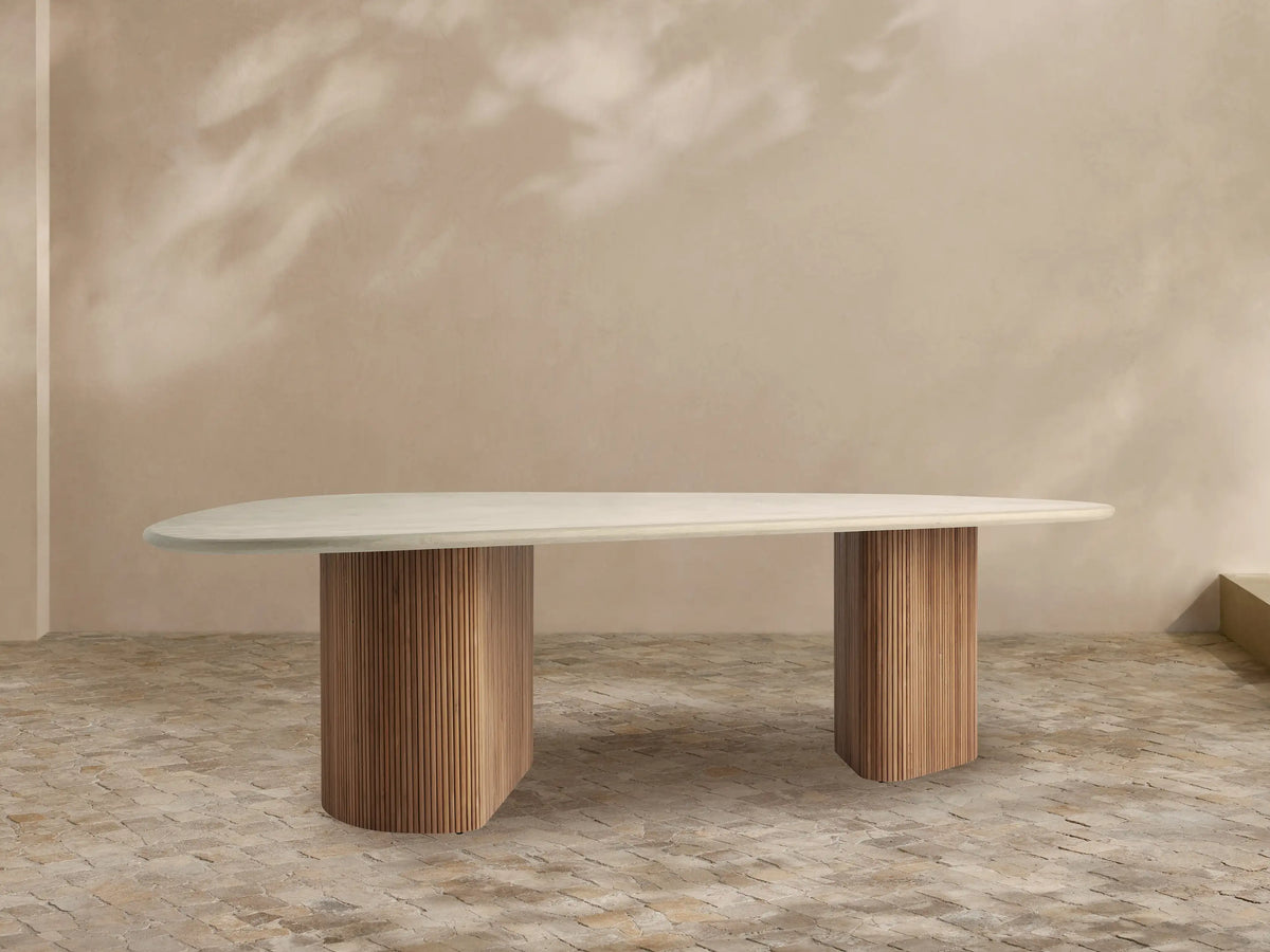 Alesso Outdoor Dining Table with an oval light gray concrete tabletop resting on two fluted natural teak wood bases. Minimalist scene.