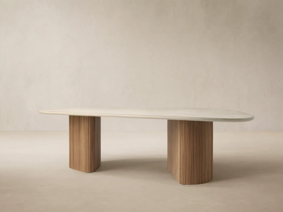 Alesso Outdoor Dining Table with an oval light gray concrete tabletop resting on two fluted natural teak wood bases. Minimalist scene.