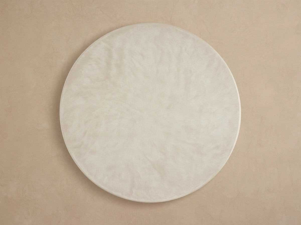 Close-up of Alesso Outdoor Round Dining Table with light gray concrete-like top, smooth edge, and fluted teak base.