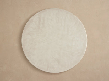 Close-up of Alesso Outdoor Round Dining Table with light gray concrete-like top, smooth edge, and fluted teak base.