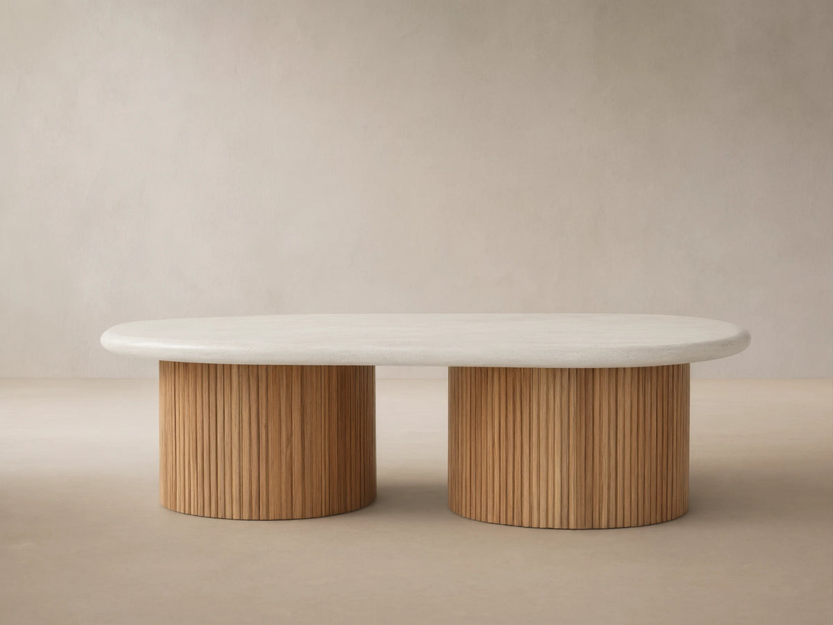Alesso Outdoor Coffee Table with oval off-white top, two semicircular bases of vertical natural teak slats on paved ground.