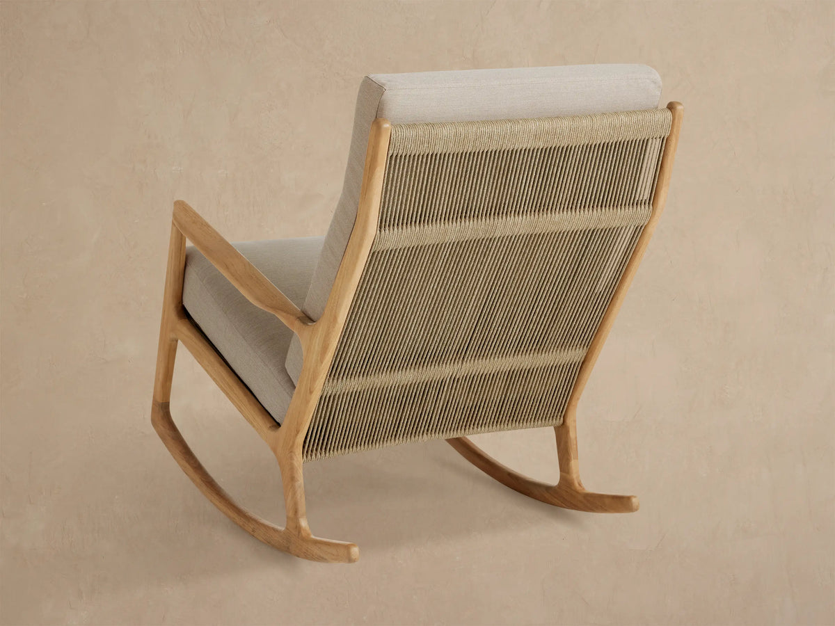 Altea Outdoor Rocking Chair, close-up angled view showing light beige cushions, natural teak wood frame & woven tan rope back.
