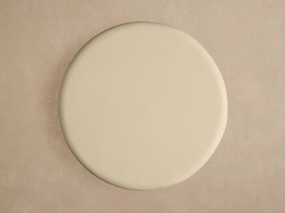 Close-up of Anami Outdoor End Table. Round, cream textured top on a light, curved teak wood base with visible grain.