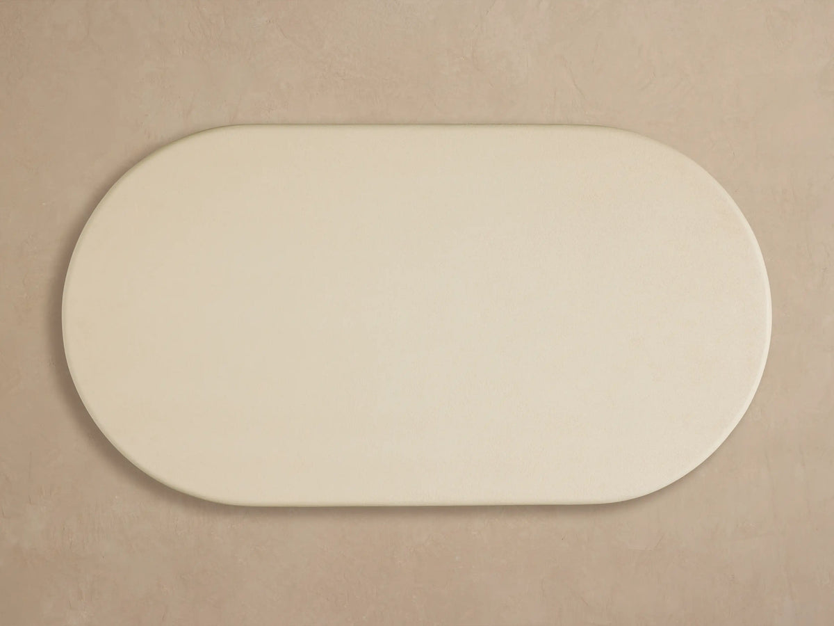 Anami Outdoor Coffee Table. Close-up of light cream rounded top on a distressed light teak wood base with visible grain.