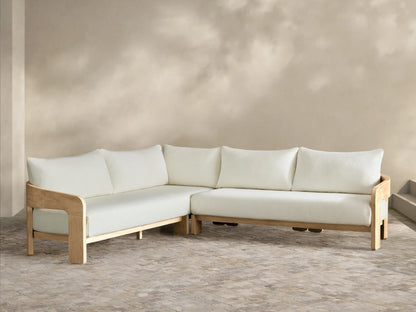 Anami Outdoor Two-Piece L-shaped sectional with light teak wood frame and off-white cushions on a stone patio.
