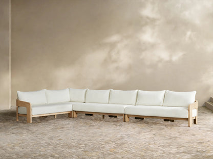 Anami Outdoor L-shaped corner sectional. Light teak wood frame with white cushions. A corner piece & two straight sections on tiled floor.