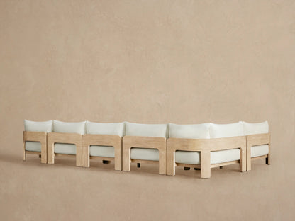Close-up of Anami Outdoor Sectional's light teak armrest with distressed texture, embracing light cream cushions.