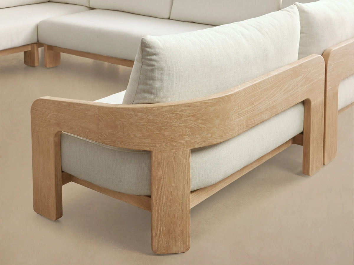 Front view of the L-shaped Anami Outdoor Three-Piece Sectional, featuring a light teak wood frame and plush white cushions.
