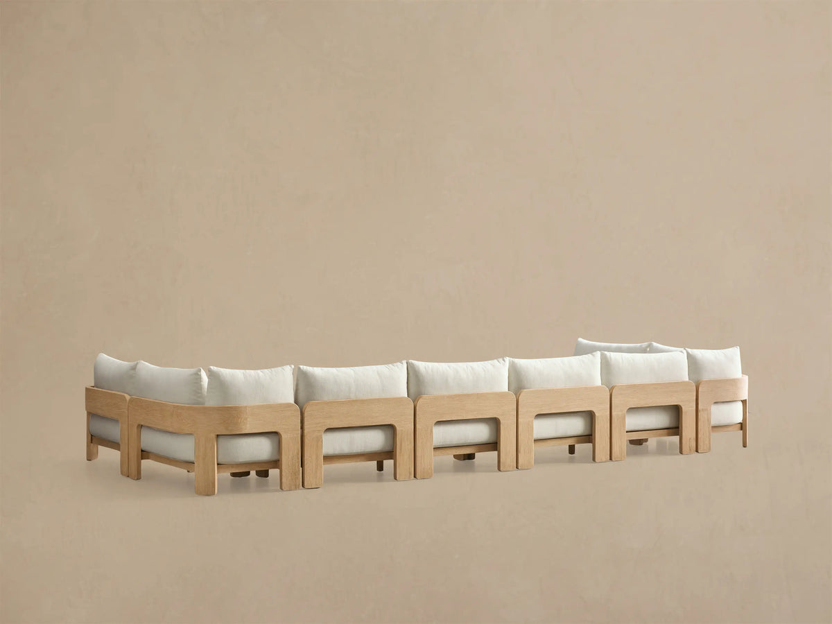 Side profile of the Anami Outdoor Four-Piece Sectional, showing a light teak wood frame and cream cushions.
