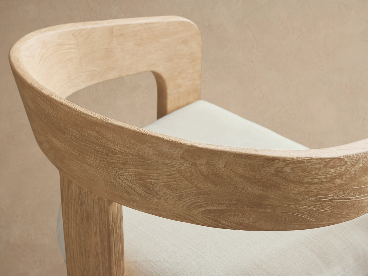 Anami Outdoor Dining Chair, light distressed teak wood with a curved back and white seat cushion, facing front.