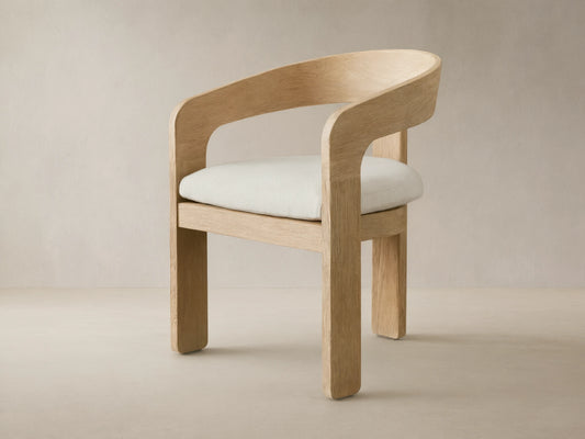 Anami Outdoor Dining Chair: light-toned, distressed teak wood with curved back and cream seat cushion on a tiled floor.