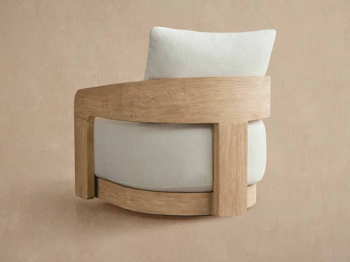 Anami Outdoor Swivel Chair armrest, light natural teak wood frame with visible grain, and cream cushion.