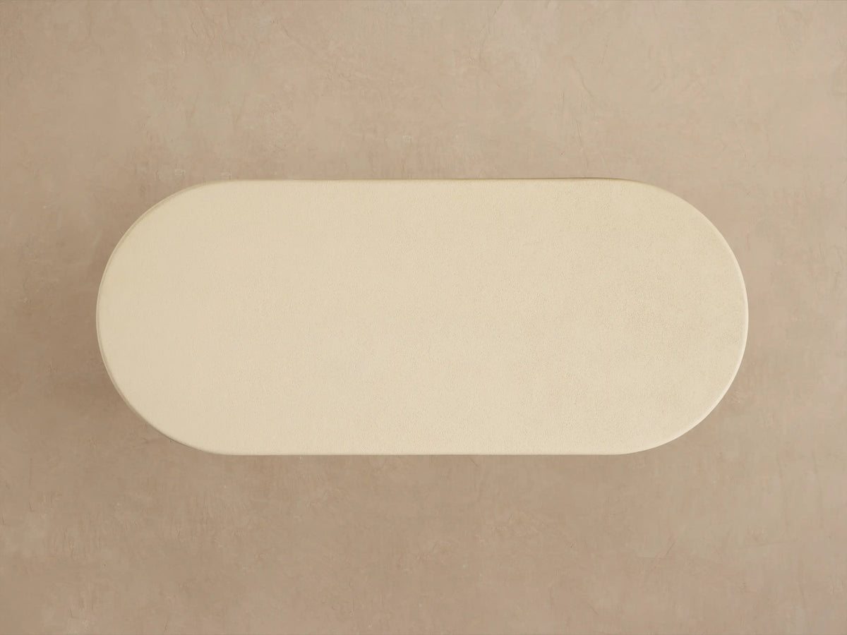 Close-up of Anami Outdoor Dining Table. Off-white textured rounded top with light brown, wire-brushed teak wood base.