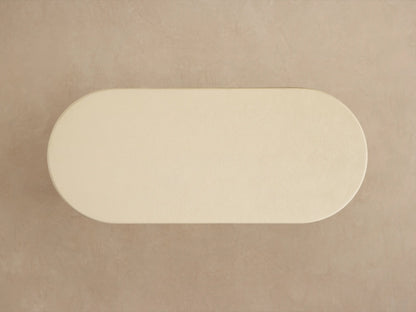 Close-up of Anami Outdoor Dining Table. Off-white textured rounded top with light brown, wire-brushed teak wood base.