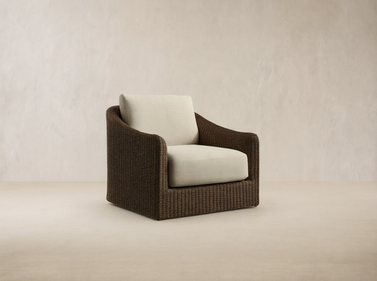 Ancona Outdoor Swivel Chair. Dark brown handwoven wicker body with thick, light beige seat and back cushions, angled right.