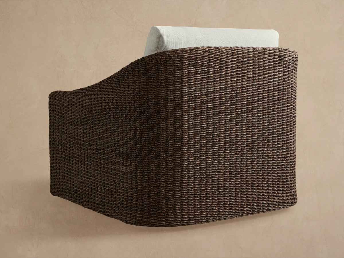 Close-up of Ancona Outdoor Swivel Chair's dark brown handwoven all-weather wicker and light off-white cushions.