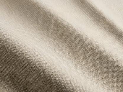Close-up of the Ancona Outdoor Sofa, showing light beige cushions and a natural brown handwoven wicker frame with a curved armrest.