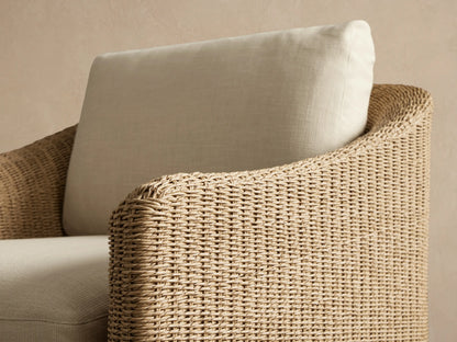 Ancona Outdoor Swivel Chair: light brown all-weather wicker frame with thick cream-colored seat and back cushions.