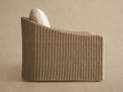 Close-up of Ancona Outdoor Swivel Chair with light tan handwoven wicker back and armrest, featuring a soft off-white cushion.