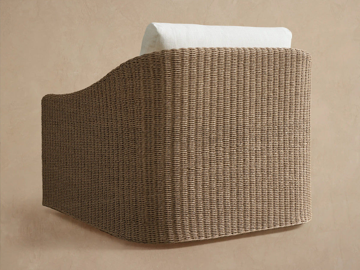 Close-up of Ancona Outdoor Swivel Chair's light brown handwoven wicker frame with a soft white back cushion.