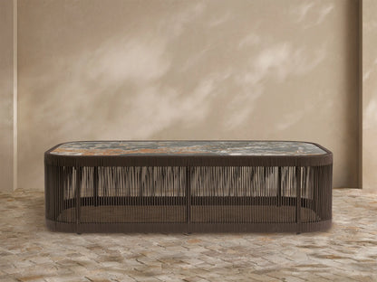 Anzio Outdoor Coffee Table: Low dark brown handwoven rope base, rectangular mottled gray & rust sintered stone top on patio.
