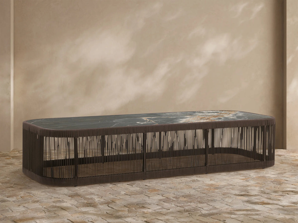 Anzio Outdoor Coffee Table: rectangular, dark brown woven rope base, marbled gray/brown sintered stone top, outdoor scene.