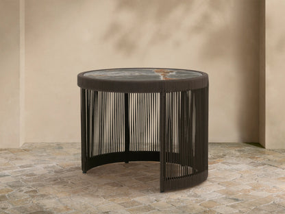 Round Anzio Outdoor Nesting End Table with a dark woven rope base and a mottled gray sintered stone top on a patio.