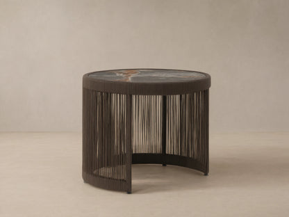 Round Anzio Outdoor Nesting End Table with a dark woven rope base and a mottled gray sintered stone top on a patio.