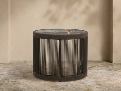 Round Anzio Outdoor Nesting End Table with a dark woven rope base and a mottled gray sintered stone top on a patio.