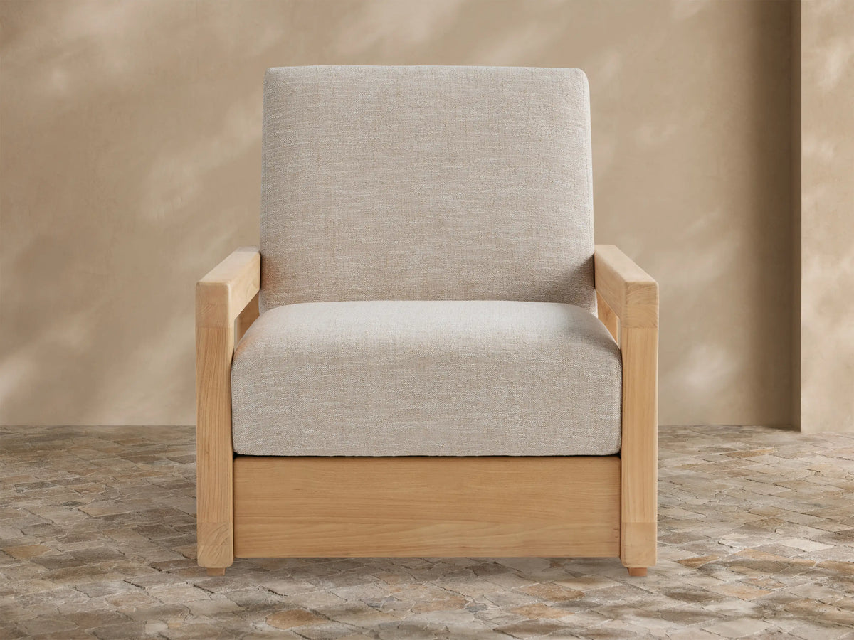 Front view of light grey Westport Outdoor Collection Cover. Tailored, textured fabric with a front seam, against a tan wall on a stone patio.