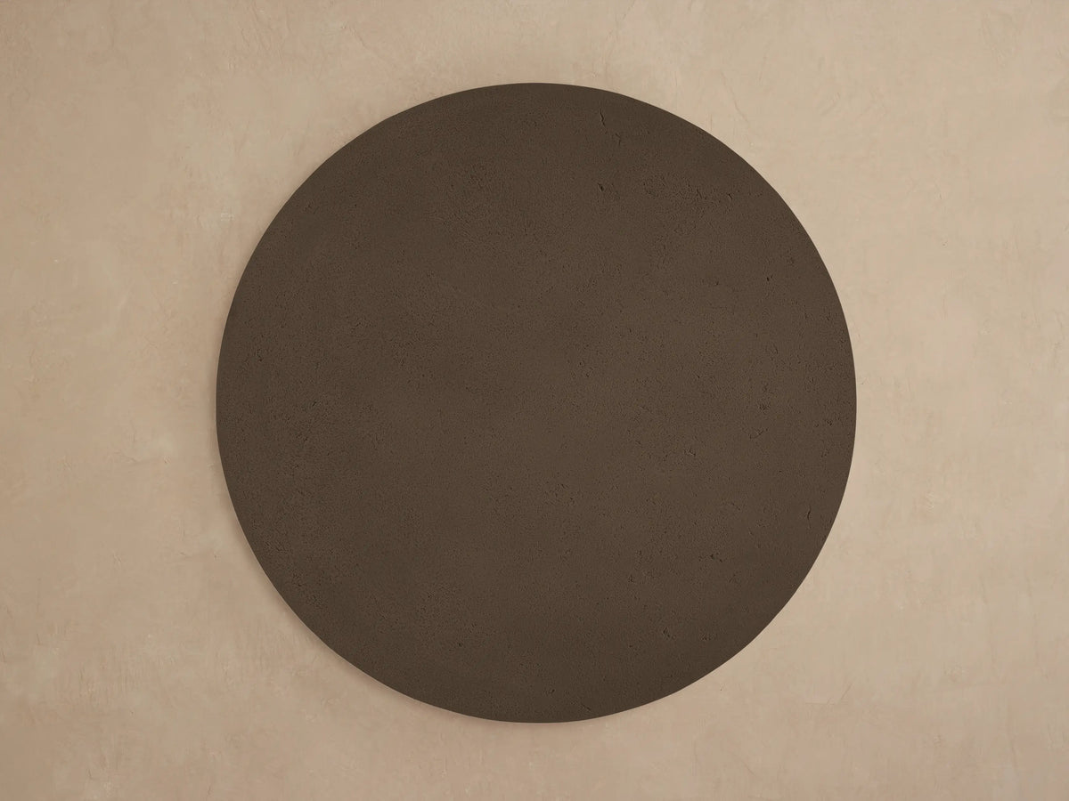 Close-up, angled view of the dark brown Azores Outdoor Round Coffee Table. Features textured faux travertine concrete finish.