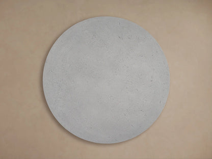 Angled close-up of Azores Round Coffee Table's light gray, textured faux travertine top and edge, with shadows.