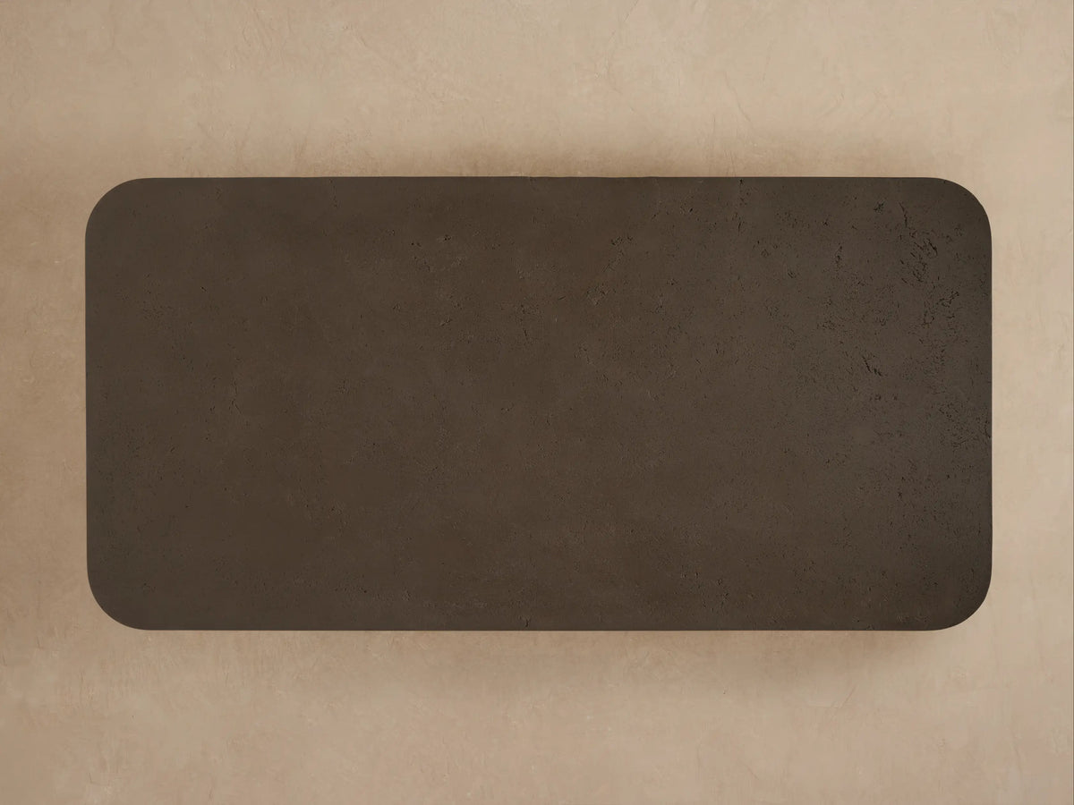 Close-up of Azores Outdoor Coffee Table, dark brown textured surface resembling concrete, with a smooth, rounded corner.