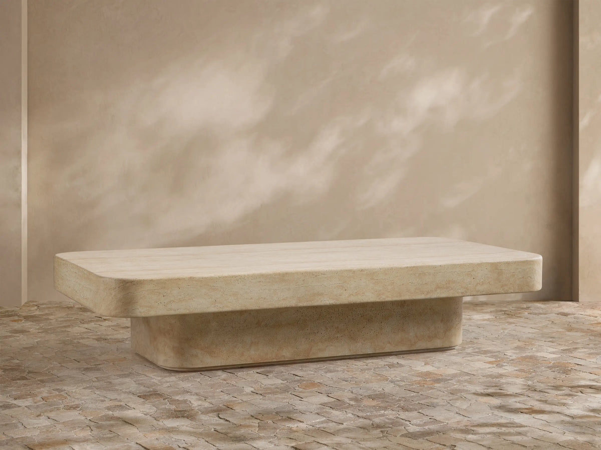 Front view of the light faux travertine Azores Outdoor Coffee Table with unique neutral veining, on a patio setting.