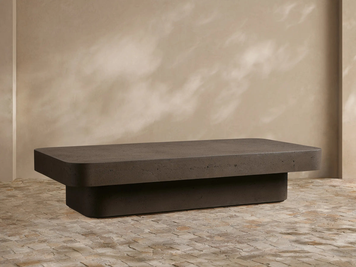 Light beige Azores Outdoor Coffee Table in faux travertine on a patio, styled with decorative white vases, an outdoor sofa, and armchair.