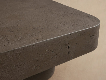 Azores Outdoor Coffee Table, a dark gray rectangular concrete-style table with rounded corners, on a light stone floor.