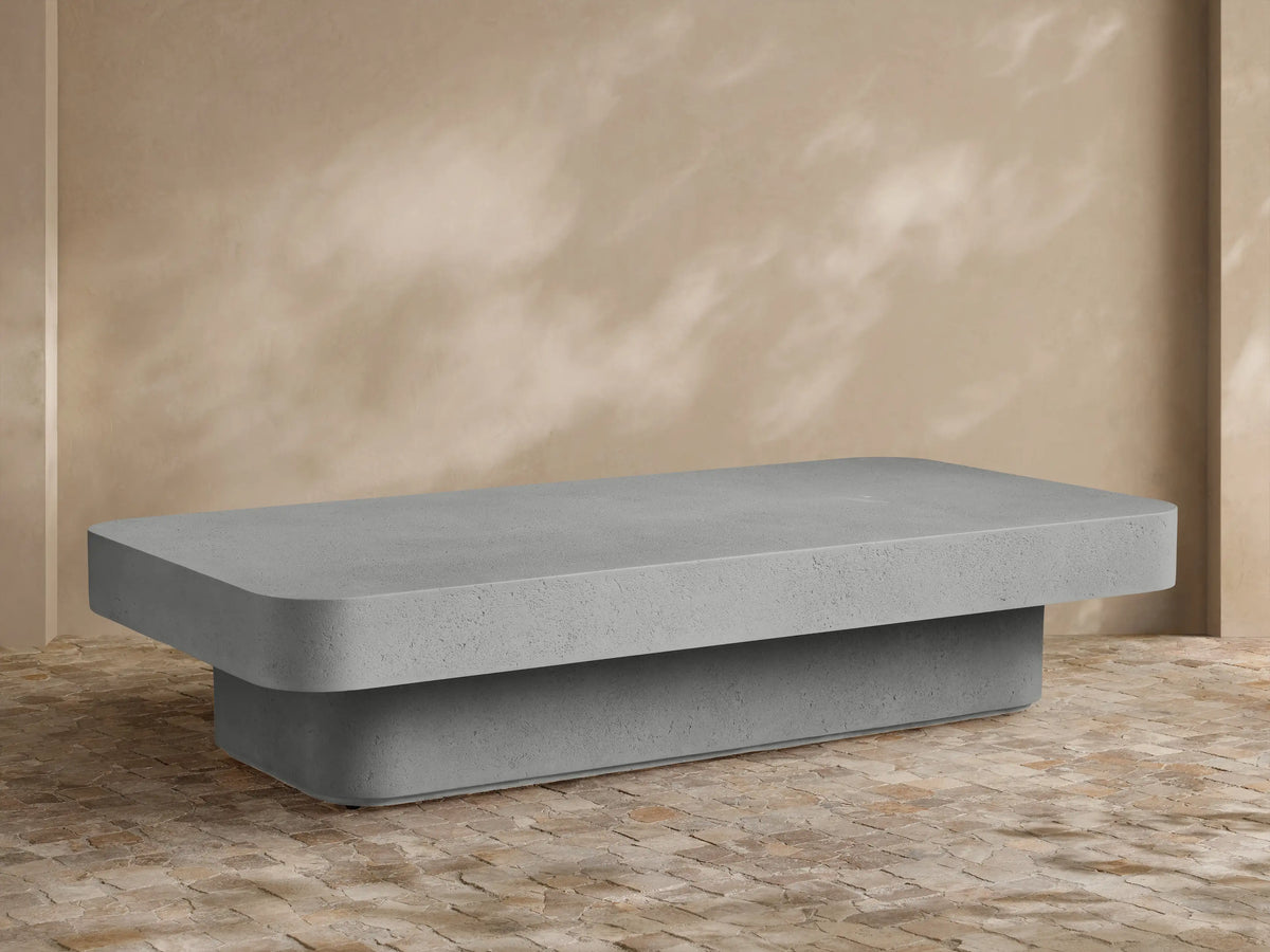 Faux travertine Azores Outdoor Coffee Table, organic-shaped, styled with three white vases on an outdoor patio.
