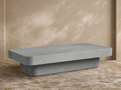Faux travertine Azores Outdoor Coffee Table, organic-shaped, styled with three white vases on an outdoor patio.