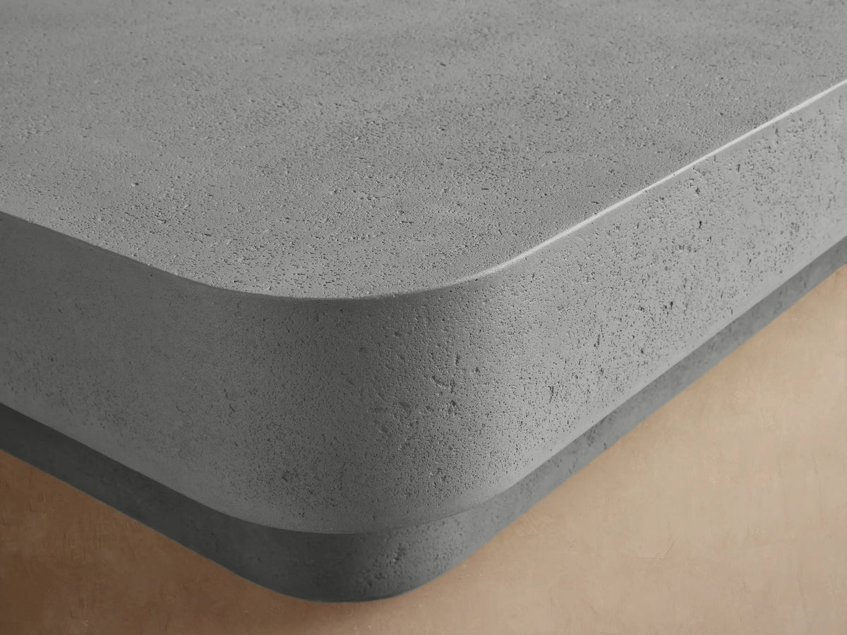 Azores Outdoor Coffee Table, light gray rectangular concrete-look table with rounded edges, on a low base, angled.